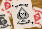 An Ace of Spades featuring a skull design, with similar Aces of other suits in the background